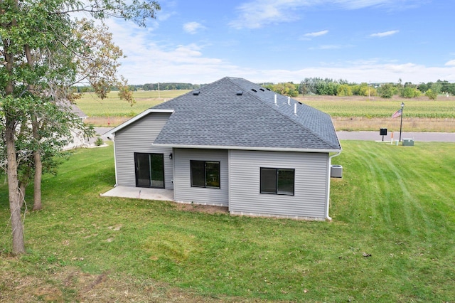 back of property with a lawn, a rural view, and a patio