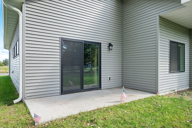 entrance to property with a lawn and a patio