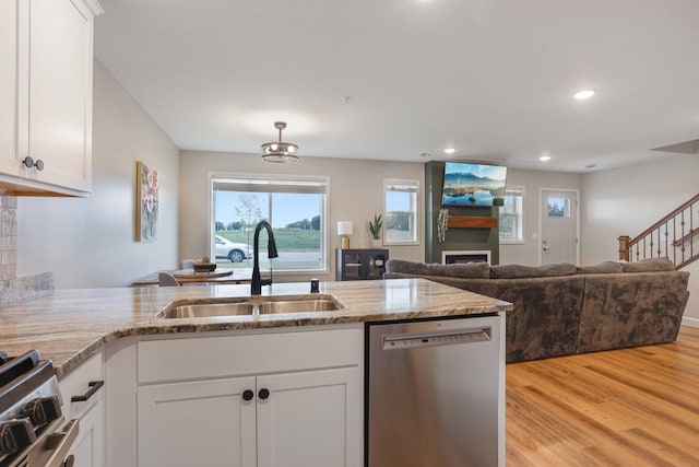 kitchen featuring sink, white cabinets, light hardwood / wood-style flooring, stainless steel appliances, and light stone countertops