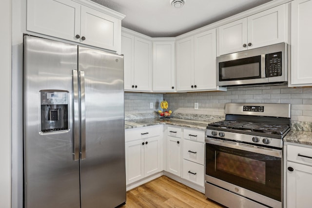 kitchen featuring light wood-type flooring, white cabinetry, stainless steel appliances, and light stone counters