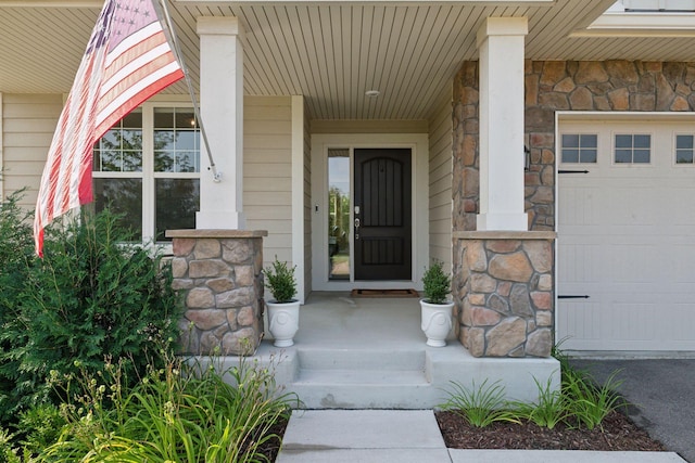 view of exterior entry featuring stone siding and an attached garage