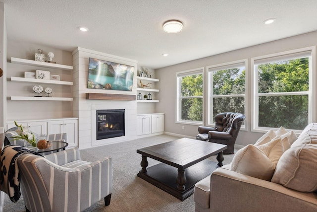 living area with light carpet, baseboards, a textured ceiling, a fireplace, and recessed lighting