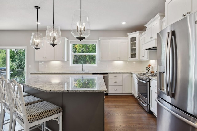 kitchen featuring glass insert cabinets, white cabinetry, appliances with stainless steel finishes, and decorative light fixtures