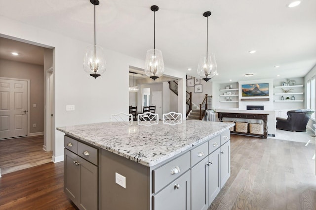 kitchen with gray cabinets, a kitchen island, pendant lighting, and open floor plan