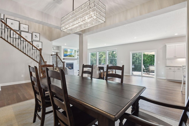 dining room featuring dark wood finished floors, recessed lighting, a glass covered fireplace, baseboards, and stairs