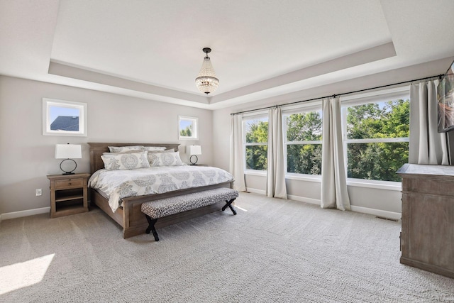 bedroom with light carpet, a tray ceiling, visible vents, and baseboards