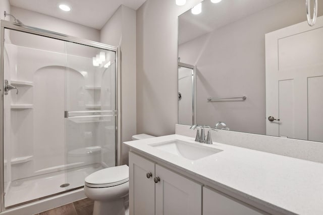 bathroom featuring toilet, a shower stall, wood finished floors, and vanity