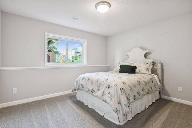 bedroom featuring a textured ceiling, dark carpet, and baseboards