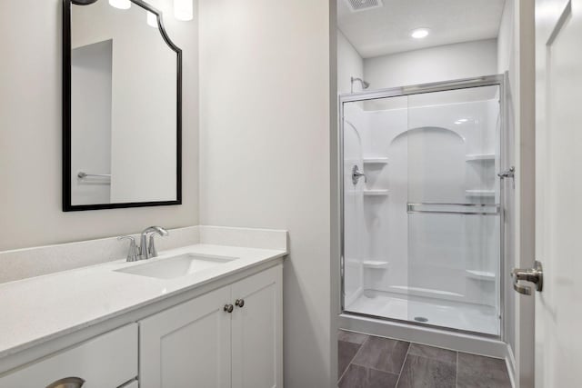 full bathroom featuring visible vents, a shower stall, and vanity