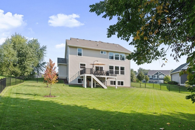 rear view of house with a fenced backyard, a yard, a wooden deck, and stairs