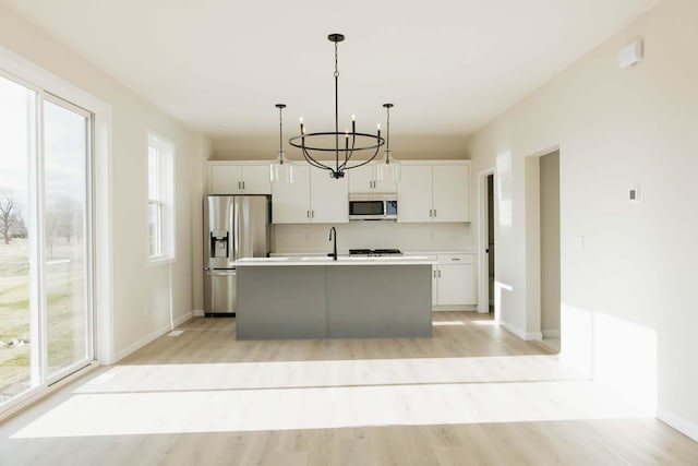 kitchen with white cabinetry, a kitchen island with sink, light hardwood / wood-style flooring, and appliances with stainless steel finishes