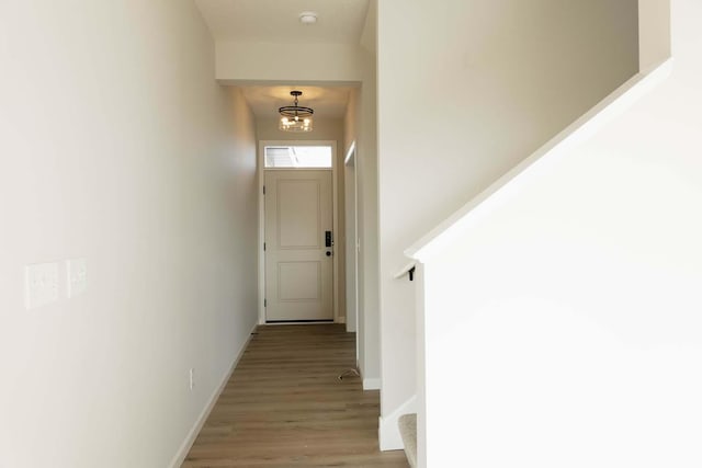 hall featuring light wood-type flooring and an inviting chandelier