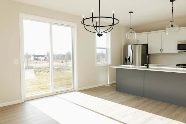 kitchen featuring white cabinets, pendant lighting, stainless steel appliances, and plenty of natural light