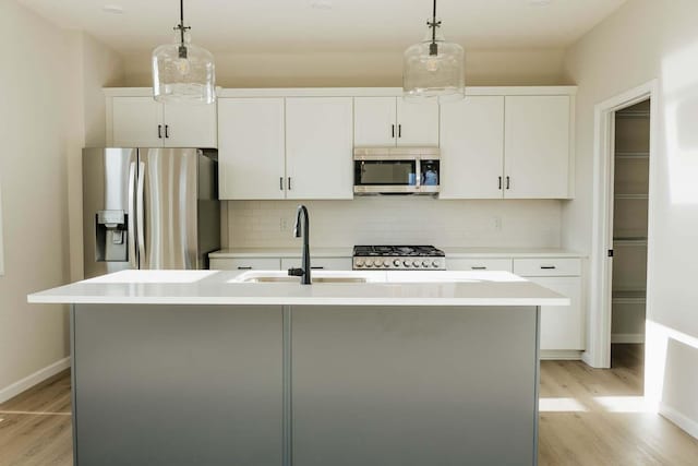 kitchen with white cabinetry, a center island with sink, and stainless steel appliances