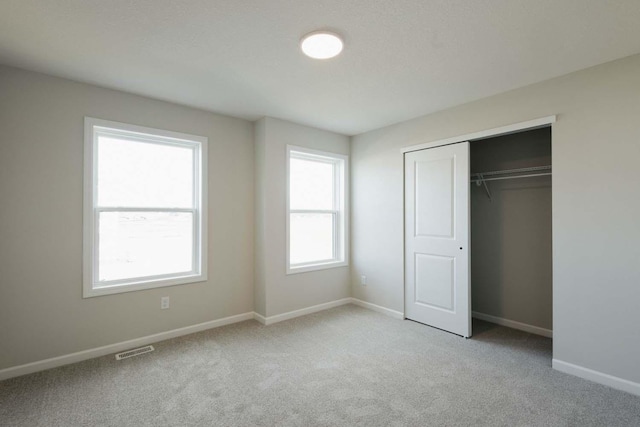 unfurnished bedroom featuring a closet and light colored carpet