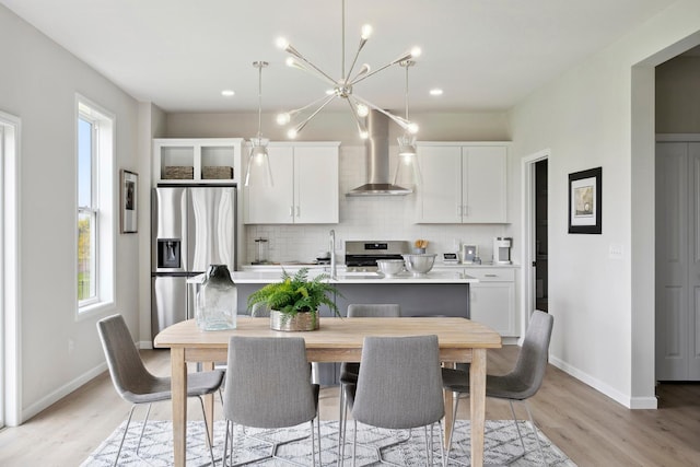 kitchen featuring white cabinets, wall chimney exhaust hood, a healthy amount of sunlight, and appliances with stainless steel finishes