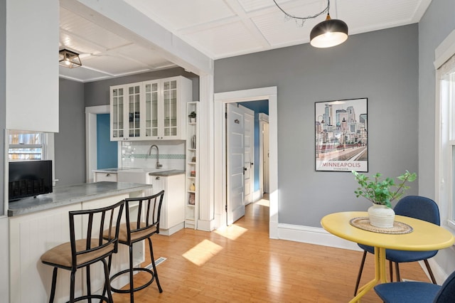 kitchen featuring backsplash, white cabinetry, light wood-type flooring, and pendant lighting