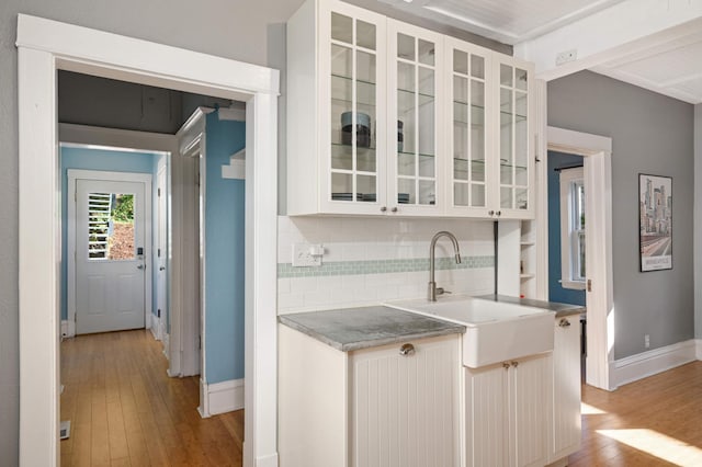 kitchen with sink, light hardwood / wood-style floors, backsplash, and white cabinetry