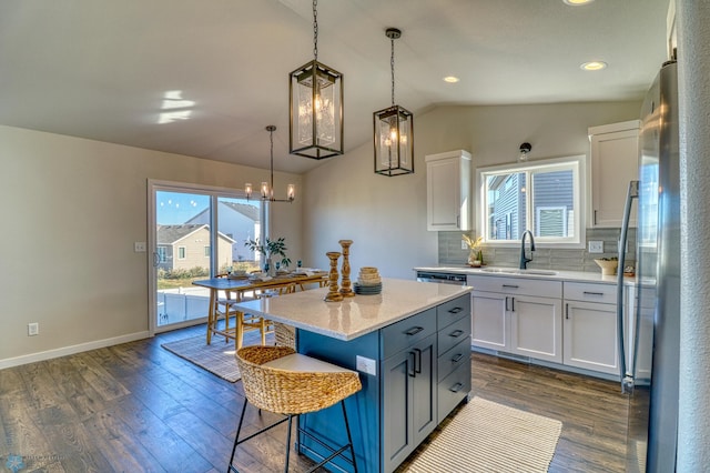 kitchen featuring a center island, white cabinetry, sink, lofted ceiling, and stainless steel fridge