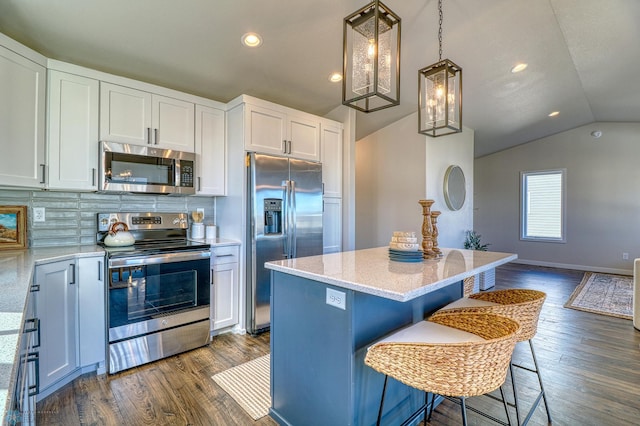 kitchen with white cabinets, appliances with stainless steel finishes, lofted ceiling, dark wood-type flooring, and a kitchen island