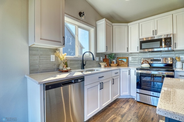 kitchen featuring light stone countertops, stainless steel appliances, white cabinetry, sink, and dark wood-type flooring