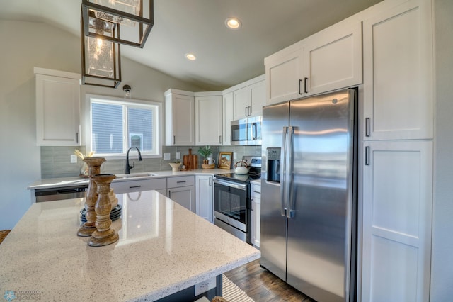 kitchen with light stone counters, sink, dark wood-type flooring, appliances with stainless steel finishes, and lofted ceiling