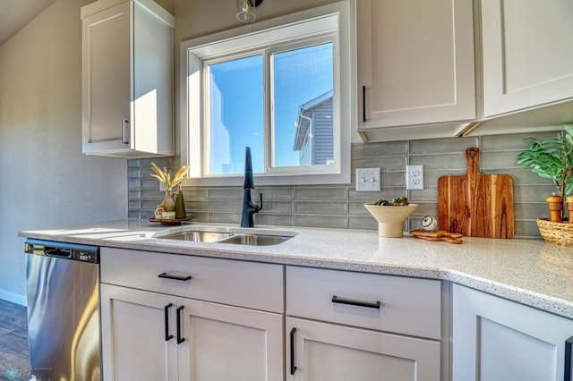 kitchen featuring light stone countertops, dishwasher, sink, decorative backsplash, and white cabinetry