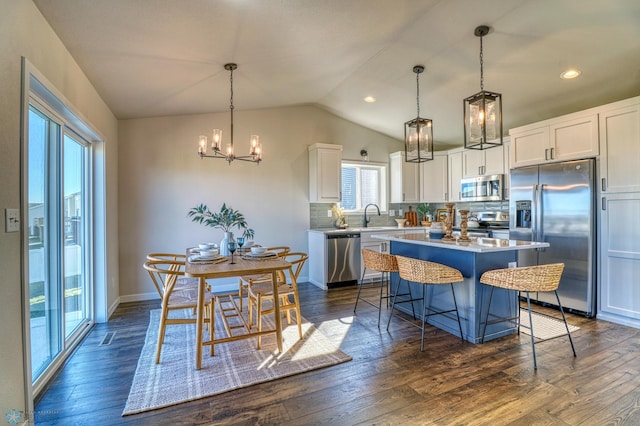 kitchen featuring stainless steel appliances, white cabinetry, lofted ceiling, dark hardwood / wood-style floors, and a kitchen island