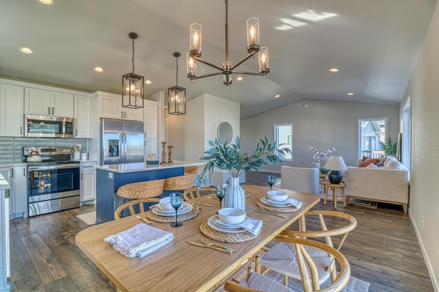 interior space featuring vaulted ceiling, dark hardwood / wood-style floors, appliances with stainless steel finishes, a center island, and white cabinetry