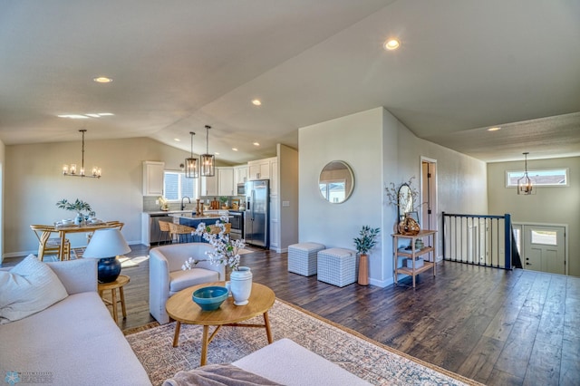 living room featuring dark hardwood / wood-style floors, a chandelier, and vaulted ceiling