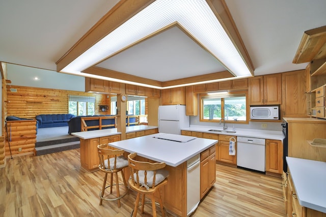 kitchen with a kitchen island, light wood-type flooring, light countertops, white appliances, and a sink