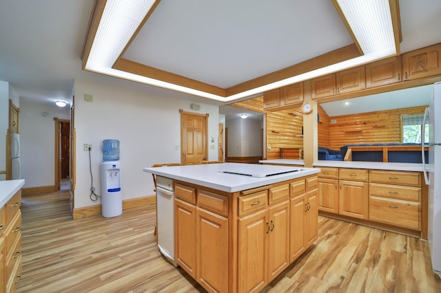 kitchen featuring a kitchen island, a tray ceiling, freestanding refrigerator, light countertops, and light wood-style floors