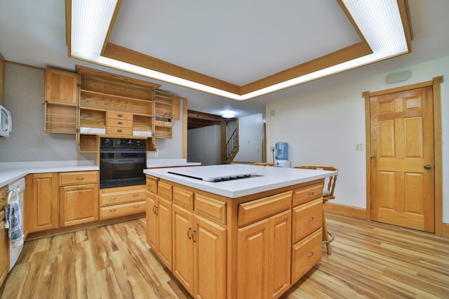 kitchen featuring black oven, a raised ceiling, light wood-style floors, and open shelves