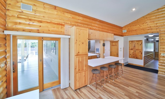 kitchen featuring a breakfast bar, a peninsula, light wood-style flooring, and light brown cabinets