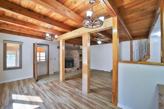 interior space featuring beam ceiling, wood finished floors, wooden ceiling, a fireplace, and stairs