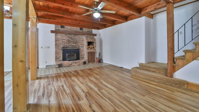 unfurnished living room with ceiling fan, stairway, beamed ceiling, wood ceiling, and wood finished floors