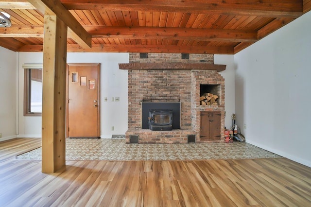 unfurnished living room with beam ceiling, wooden ceiling, a wood stove, and wood finished floors