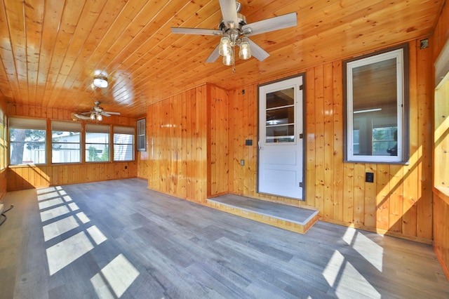 interior space with ceiling fan, wood finished floors, wooden walls, and wooden ceiling