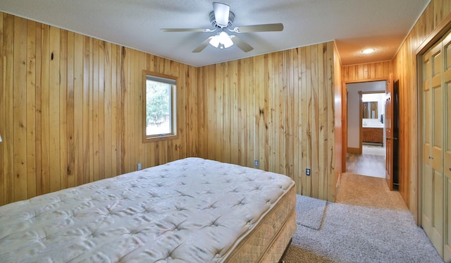 carpeted bedroom with wooden walls, a ceiling fan, and a textured ceiling