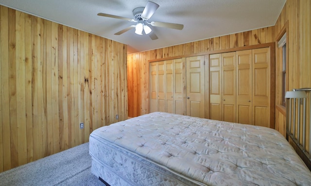 bedroom with ceiling fan, a closet, wood walls, a textured ceiling, and carpet flooring