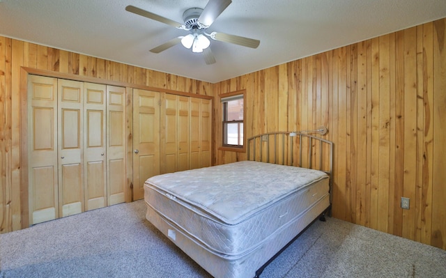 bedroom featuring wooden walls, ceiling fan, and carpet