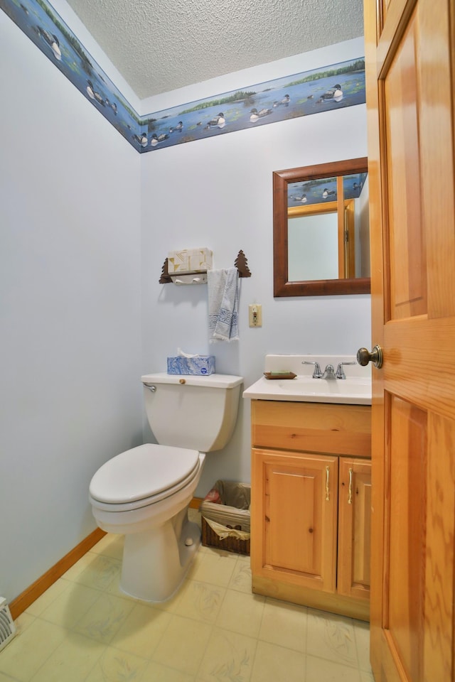 bathroom with baseboards, toilet, vanity, and a textured ceiling