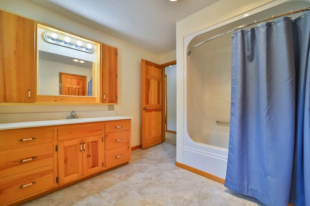 bathroom featuring a textured ceiling, shower / bath combo with shower curtain, vanity, and baseboards