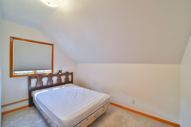 bedroom featuring carpet flooring, a textured ceiling, lofted ceiling, and baseboards