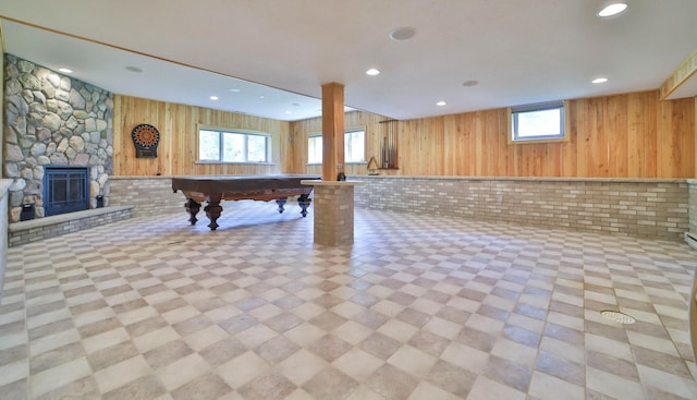 recreation room with wooden walls, recessed lighting, and a fireplace