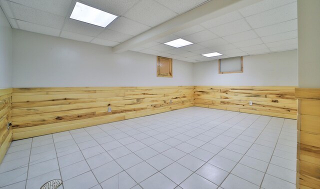 unfurnished room with a drop ceiling, a wainscoted wall, and wooden walls