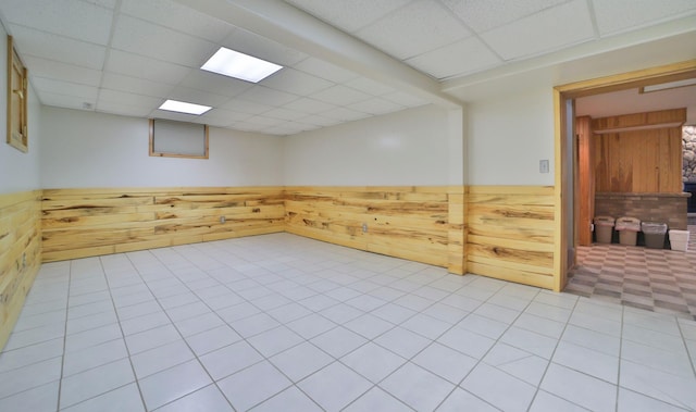 spare room featuring wooden walls, a paneled ceiling, and a wainscoted wall