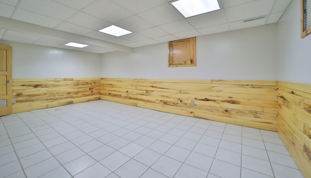 spare room with a drop ceiling, wooden walls, and wainscoting