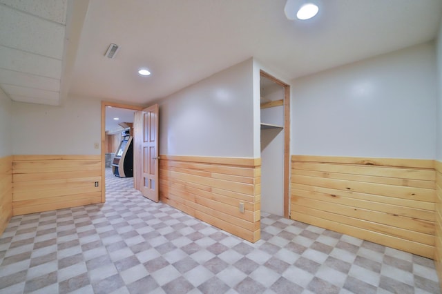 interior space with tile patterned floors, visible vents, wooden walls, and wainscoting