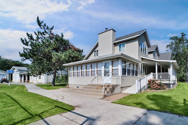 view of front of home with a front lawn, covered porch, a sunroom, and a chimney